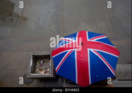 Una persona che ripara dalla pioggia sotto una bandiera europea ombrello in Trafalgar Square, Londra centrale. Foto Stock