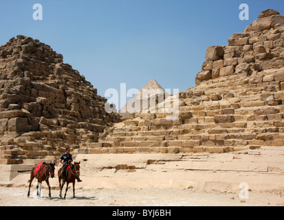 Un ragazzo egiziano passeggiate a cavallo, e porta un altro, nella parte anteriore delle piramidi di Giza in Egitto. Foto Stock