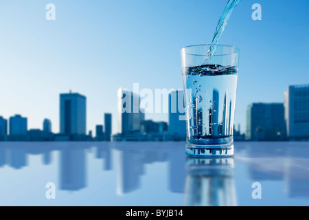 Vetro di acqua da bere colata Skyline scena urbana Foto Stock