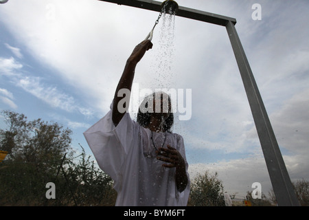 Un membro dell'Eritrea comunità ortodossa di prendere una doccia con acqua dal fiume Giordano presso il sito battesimale Qaser el Yahud Kasser anche o Qasser al Yehud il nome ufficiale della parte occidentale del sito tradizionale del Battesimo di Gesù da Giovanni Battista nel fiume Giordano regione Valle della West Bank Israele Foto Stock