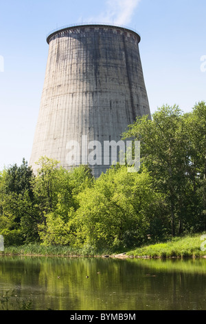 Torre di raffreddamento con acqua e alberi in primo piano Foto Stock