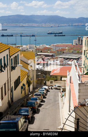 Tradizionale tipica Gibilterra street / strade / road, con case & automobili parcheggiate, guardando oltre il mare verso la Spagna & terra spagnola. Foto Stock