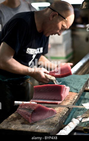 Lavoratore il taglio di tonno presso il mercato del pesce di Tsukiji Foto Stock