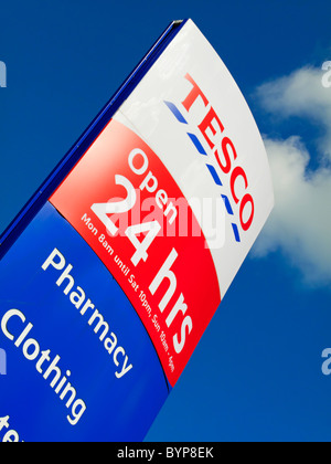 Cartello fuori Tesco 24 ore di apertura supermercato nel Regno Unito con il blu del cielo dietro Foto Stock