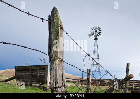 Stati Uniti d'America, North Dakota, Watford City, Windmill arrugginiti e filo spinato a azienda abbandonata sito su prairie Foto Stock