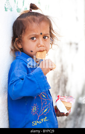 Villaggio indiano il neonato ragazza di mangiare i biscotti a partire da un pacchetto. Andhra Pradesh, India Foto Stock