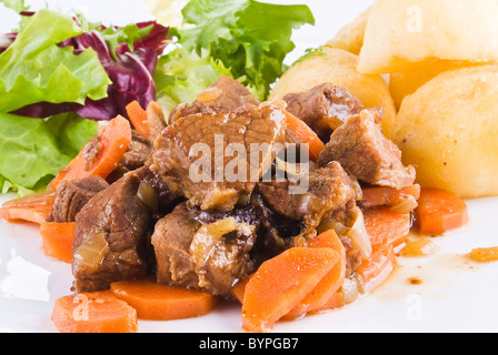 Pasto di stufati di carne di manzo con patate arrosto e insalata fresca Foto Stock