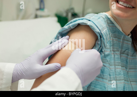 Medico applicazione di bendaggio adesivo al braccio del paziente Foto Stock