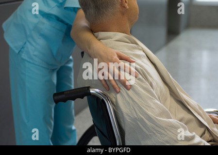 L'infermiera aiutando paziente in sedia a rotelle e tagliato Foto Stock