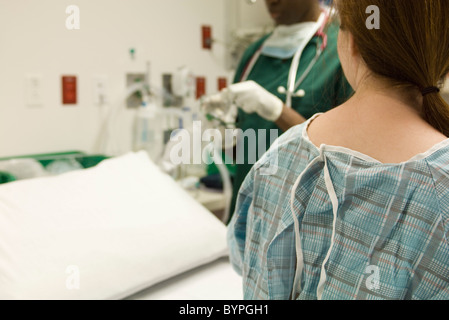 Paziente a guardare come infermiera prepara le apparecchiature mediche Foto Stock