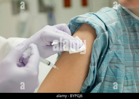 Medico posizionando la garza sul braccio del paziente dopo la somministrazione di un colpo Foto Stock