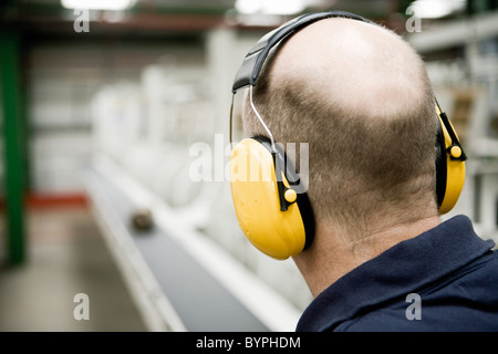 Tappeto operaio di fabbrica indossando insonorizzate le cuffie di protezione Foto Stock