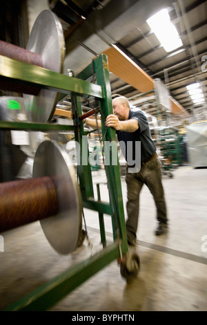 Operaio tessile impostazione di subbi di ordito sulla macchina di tessitura dei tappeti fabbrica piastrelle Foto Stock