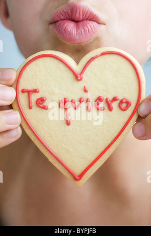 Donna raggrinzamenti labbra, tenendo premuto fino a forma di cuore cookie Foto Stock