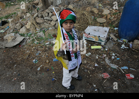 Un giovane ragazzo palestinese avvolto con la bandiera palestinese durante un raduno settimanale contro la costruzione della controversa le barriere di separazione essendo costruito da Israele in Cisgiordania villaggio di Bil'in Israele Foto Stock