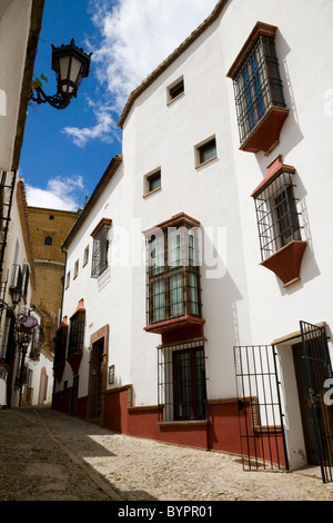 Tipico tradizionale spagnolo torna in ciottoli street / strade / per la circolazione su strada e gli edifici & blue sky nella città bianca di Ronda, Spagna. Foto Stock