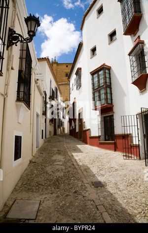 Tipico tradizionale spagnolo torna in ciottoli street / strade / per la circolazione su strada e gli edifici & blue sky nella città bianca di Ronda, Spagna. Foto Stock
