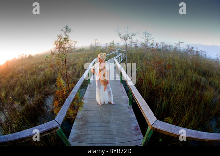 Giovane donna in abiti alla moda in piedi sulla passerella di legno in natura Foto Stock