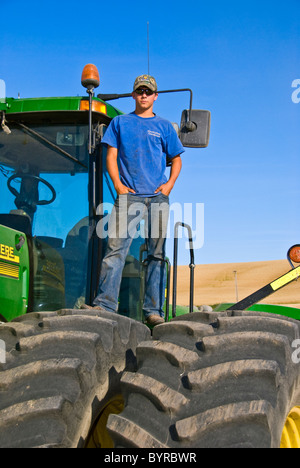 Un giovane agricoltore in cima il suo trattore durante una breve pausa da raccolto nella regione di Palouse / vicino al Pullman, Washington, Stati Uniti d'America. Foto Stock