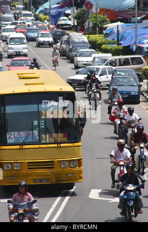 Un grande giallo bus della città è la tessitura attraverso il traffico pesante su una strada trafficata nel quartiere di Georgetown di Penang, Malaysia. Foto Stock