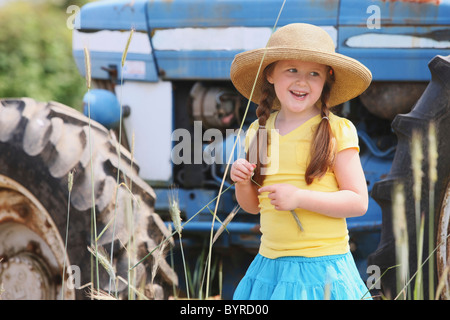 Una ragazza che indossa un grande cappello di paglia in piedi nella parte anteriore di un trattore; troutdale, Oregon, Stati Uniti d'America Foto Stock