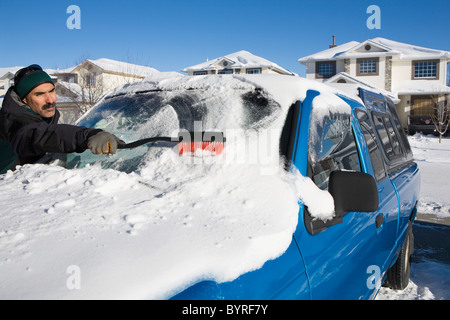 Uomo di neve di spazzolatura off di un veicolo con parabrezza; Calgary, Alberta, Canada Foto Stock