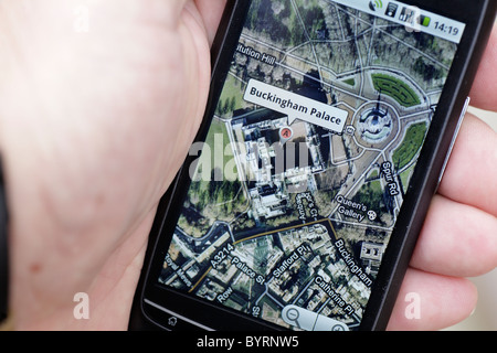 Uomo che guarda il GPS google maps mappa di Buckingham Palace di Londra sul touch screen smartphone in un hotspot wifi closeup Foto Stock