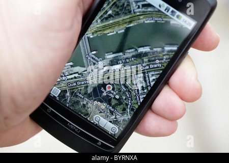 Uomo che guarda il GPS google maps Mappa di Parigi Torre Eiffel su un touch screen smartphone in un hotspot wifi closeup ombra della torre Foto Stock