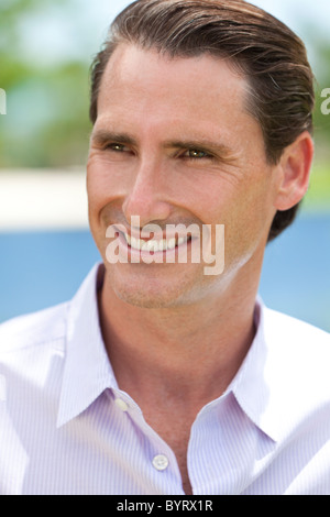 Un ritratto all'aperto di sorridere felice e bello uomo di mezza età shot con luce solare contro uno sfondo naturale Foto Stock