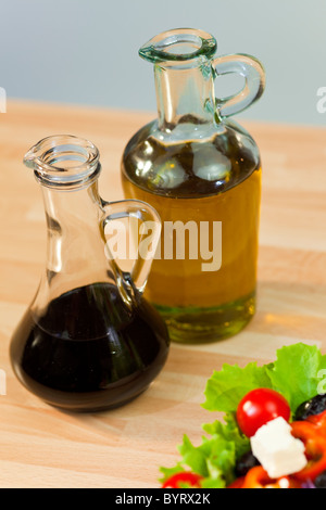 Le bottiglie di olio di oliva e aceto balsamico condimento con lattuga fresca pomodoro pepe rosso oliva la cipolla e formaggio feta insalata Foto Stock