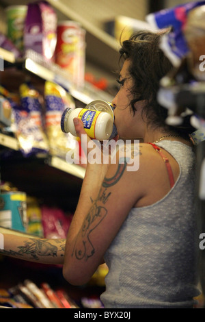 Amy Winehouse sul suo modo di negozi dove si mangia un pacchetto di patatine poi acquista alcuni tonno e mayonaise Londra Inghilterra - Foto Stock