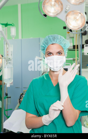 Infermiera in scrubs mettendo sul guanti Foto Stock