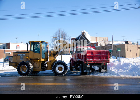 Il caricatore frontale e il camion la rimozione di neve dalla strada dopo la recente tempesta di neve Owosso Michigan STATI UNITI Foto Stock