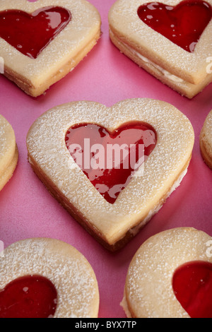 Vicino la fotografia di un cuore di biscotto a forma su sfondo rosa, biscotti in background Foto Stock