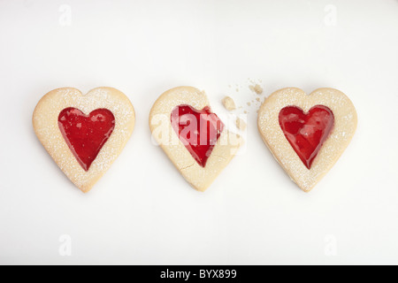 Fotografia di tre a forma di cuore biscotti su sfondo bianco, centro biscotto rotto Foto Stock