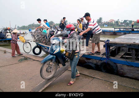 Il Vietnam il caricamento di scooter e biciclette di una chiatta per attraversare il fiume a Hoi An Foto © Julio Etchart Foto Stock