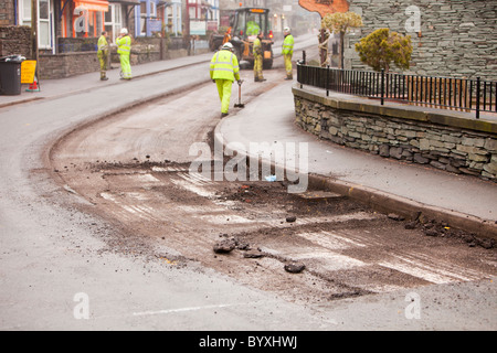 Resurfacing il lavoro che si svolge in Ambleside dopo le inondazioni e duro inverno meteo causato grave erosione della superficie stradale. Foto Stock