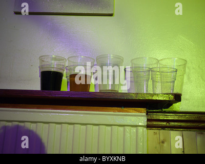 Vuoto e mezzo vuoto bicchieri da birra in un pub di Londra Foto Stock