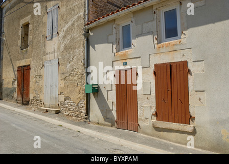 Case di pietra e gli edifici con porte verniciate e persiane linea a street nella piccola cittadina francese di St Hilaire La Palud, Francia Foto Stock