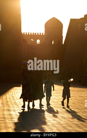 Uzbeko famiglia nel vecchio Khiva. Guardando verso la porta occidentale al tramonto. Uzbekistan Foto Stock