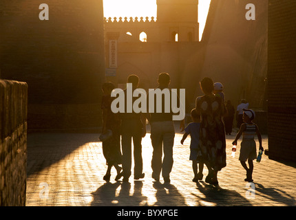 Uzbeko famiglia su un viaggio turistico della vecchia Khiva. Guardando verso la porta occidentale al tramonto. Uzbekistan Foto Stock