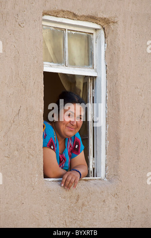 Ritratto di una donna uzbeko in stile locale e costumi alla finestra del suo adobe casa murata, Khiva, Uzbekistan Foto Stock