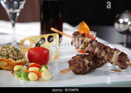 Gli spiedini di carne con pomodoro e riso su un piatto bianco Foto Stock