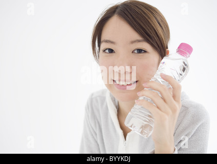 Giovane donna tenendo una bottiglia di acqua minerale Foto Stock