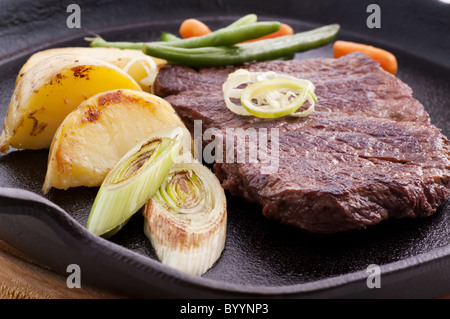 Un pezzo di carne alla griglia in una padella di ghisa con verdure, primo  piano Foto stock - Alamy