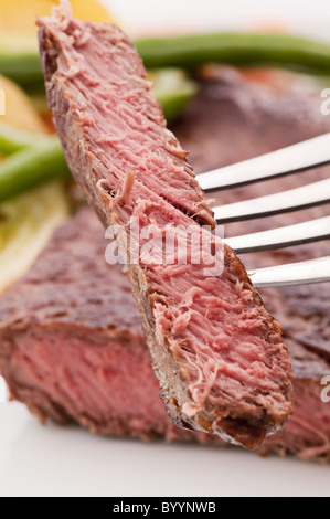 Bistecca di manzo tritata sulla forcella con verdura in background Foto Stock