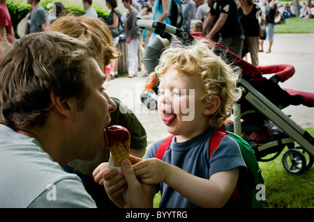 Un padre condivide un cono gelato con suo figlio. St Vincennes Park, Parigi Foto Stock