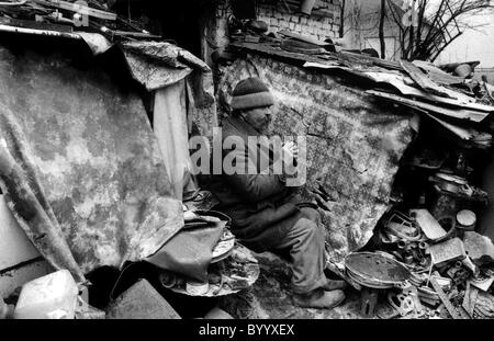 Uomo seduto in resti della sua casa distrutta in Bosnia Erzegovina la guerra Foto Stock