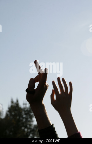 Due persone con le braccia sollevate in caso all'aperto Foto Stock