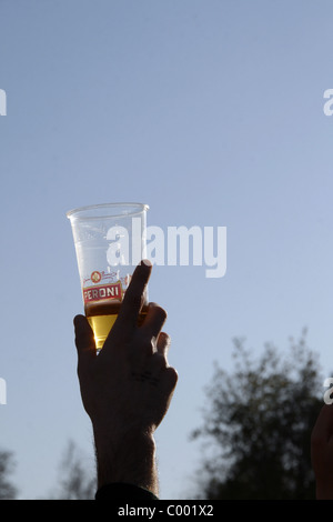 Persona in possesso di un bicchiere di plastica della Peroni birra chiara Foto Stock